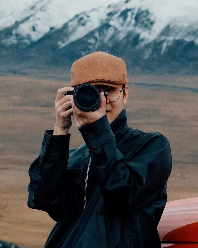 Hardy holding a camera in front of snowy mountains