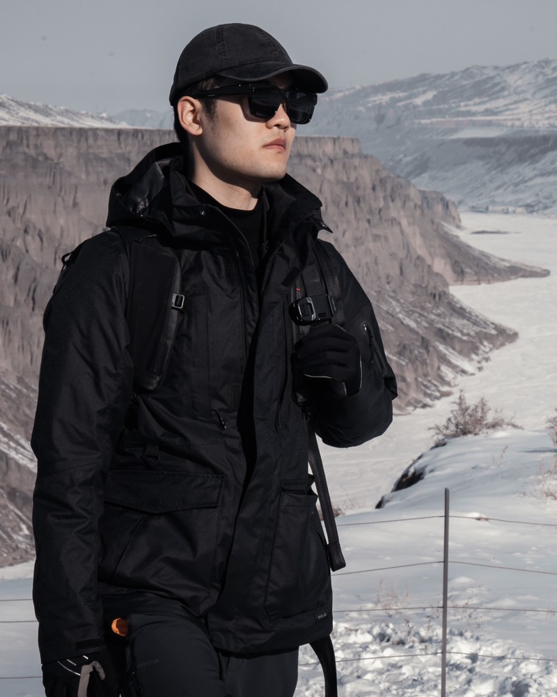 Hardy standing in a black outdoor jacket in front of a snowy canyon landscape