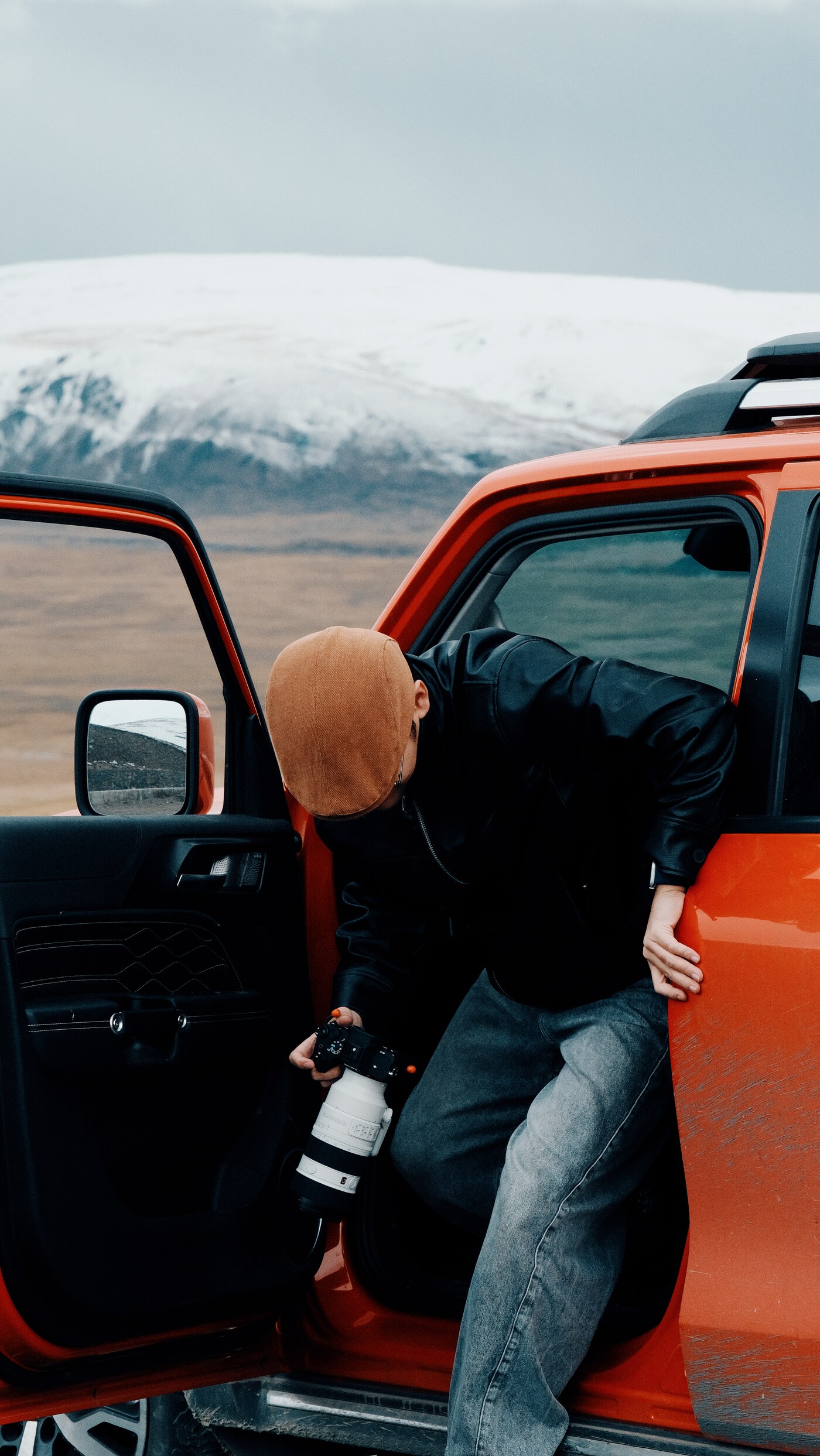 Photographer beside an orange car in the mountains